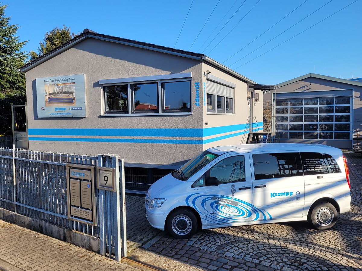 Klumpp Wasserstrahlschneiden-Station mit blau-weißem Firmenfahrzeug auf gepflastertem Hof in Altlußheim.