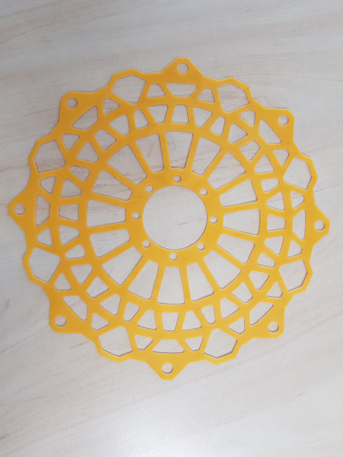 Gelbe Edelstahl-Schablone mit geometrischem Blumenmuster und Aussparungen, Wasserstrahlschnitt-Beispiel Klumpp.