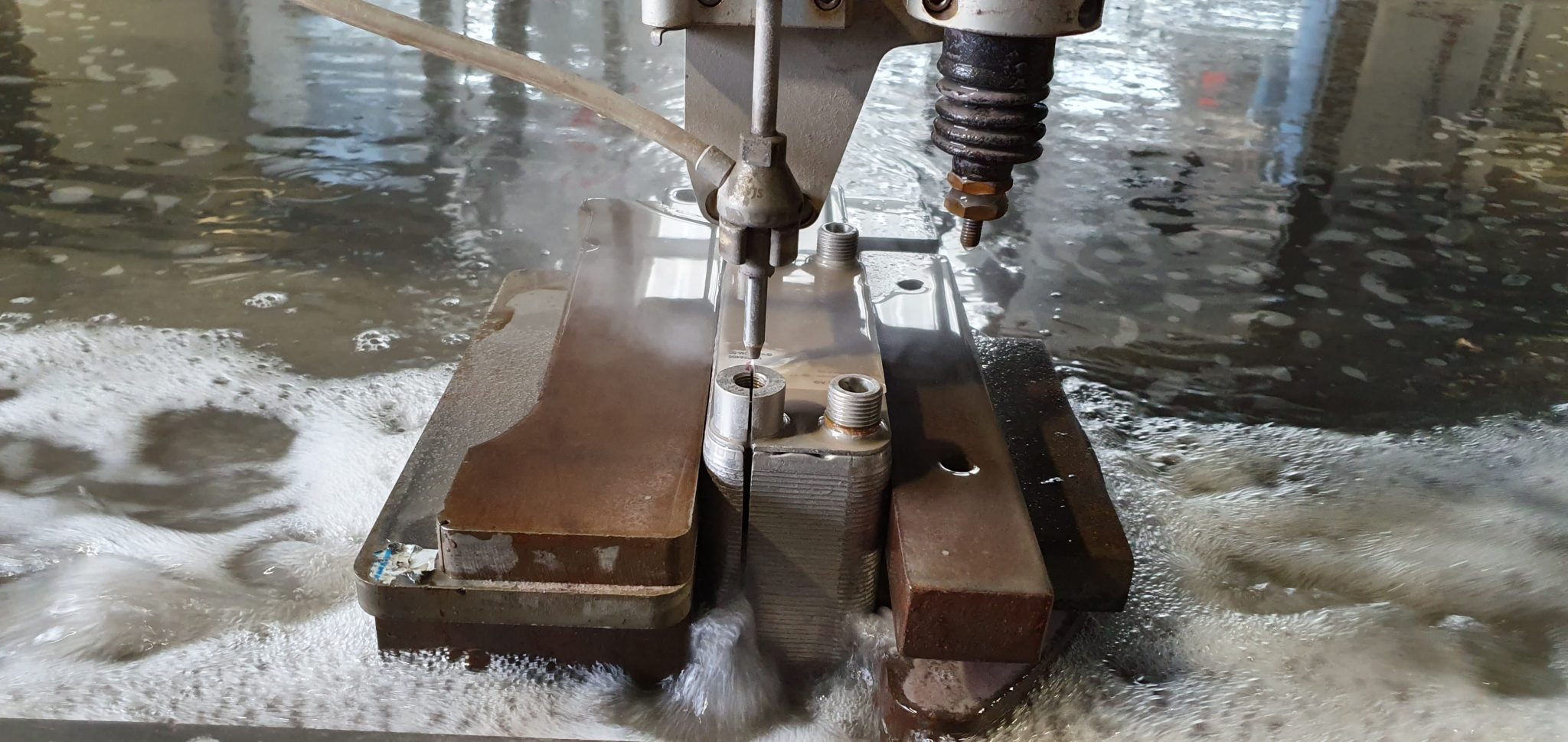Wasserstrahlschneidemaschine bearbeitet Stahlblech präzise mit Hochdruckwasserstrahl in Industriewerkstatt.