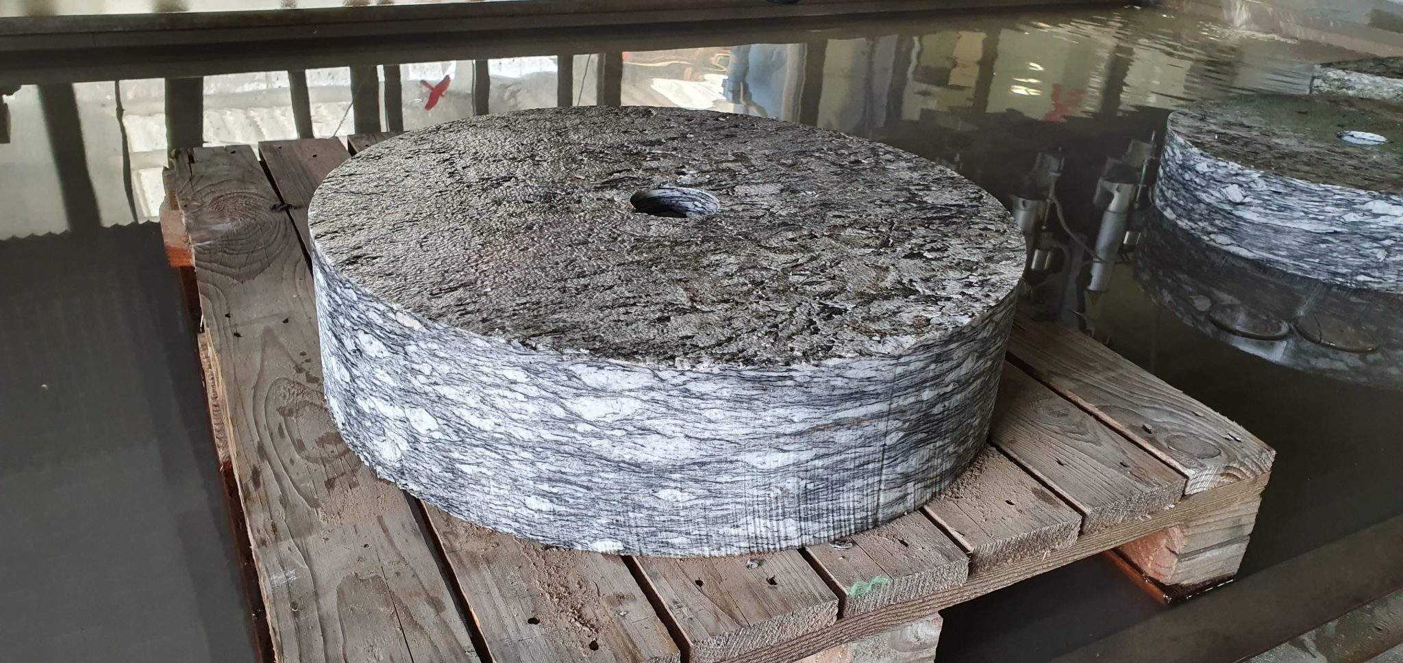 Großformatige Edelstahlscheibe mit Loch auf Holzpalette in Werkstatt, Wasserstrahlschnitt-Verarbeitung, Klumpp Altlußheim.