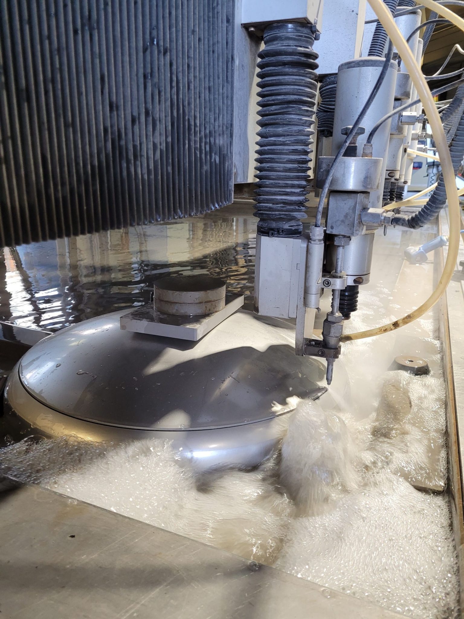 Wasserstrahlschneidanlage bei Klumpp schneidet Edelstahlplatte präzise durch Hochdruckwasserstrahl in Industriewerkstatt.