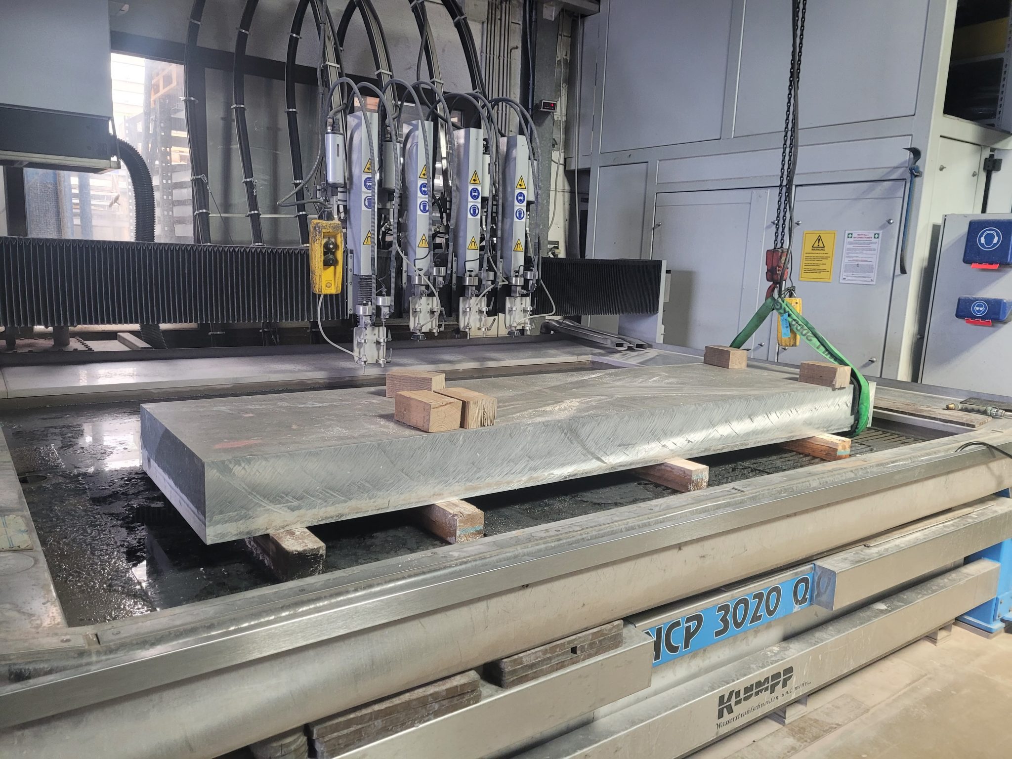 Wasserstrahlschneidemaschine YCP 3020 mit Metallplatte beim Schneideprozess in der Werkstatt von Klumpp Edelstahlverarbeitung.