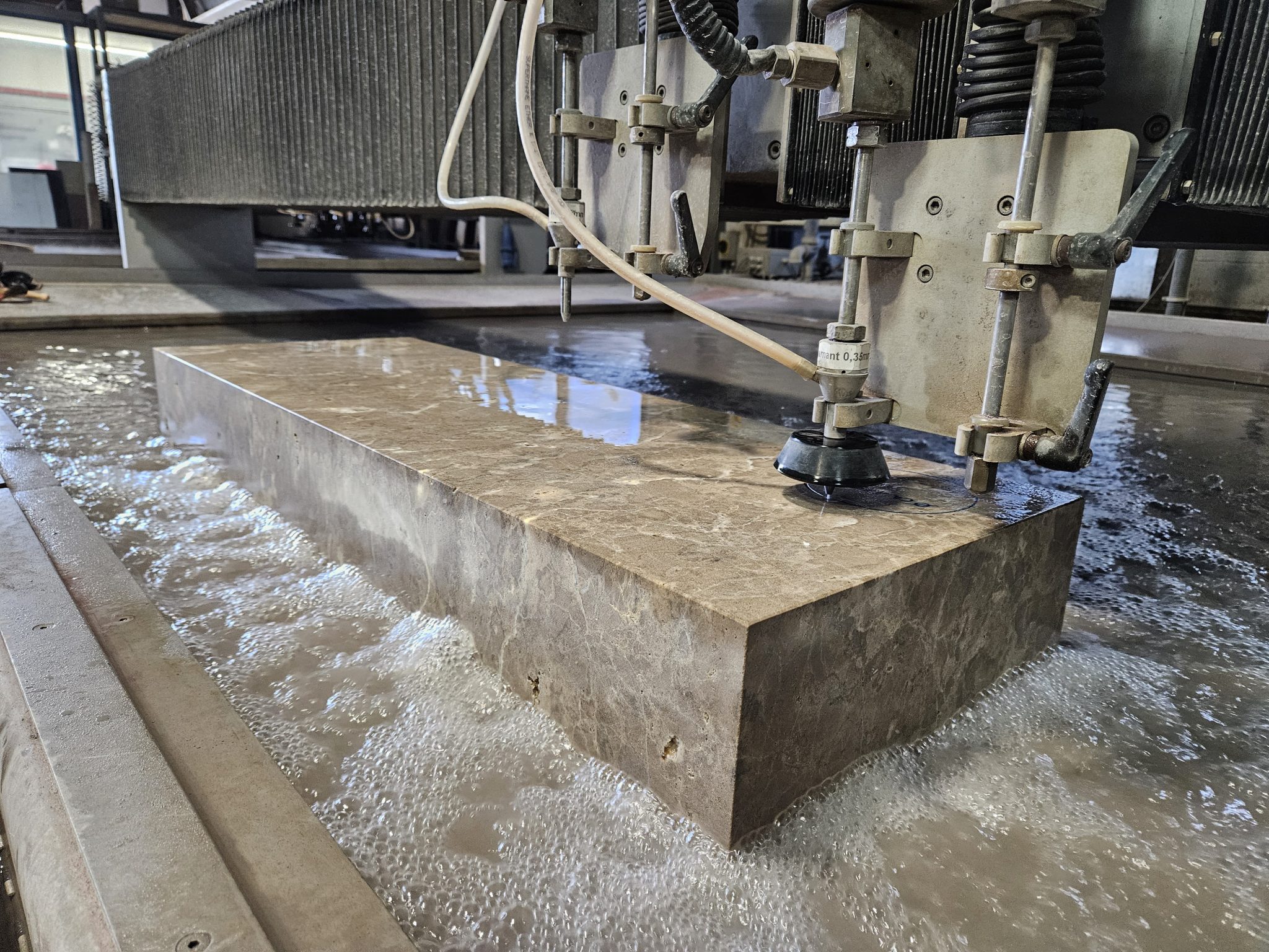 Wasserstrahlschnitt-Anlage schneidet Edelstahlblock präzise, Wasserstrahltechnologie in modernem Industriebetrieb.