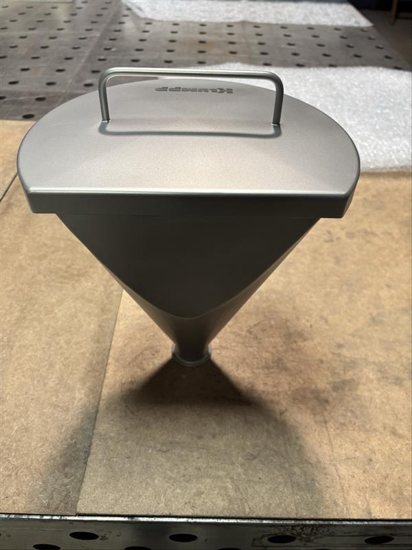 Edelstahl-Behälter mit Deckel und Griff, konischer Form, auf Betonboden in Werkstatt.