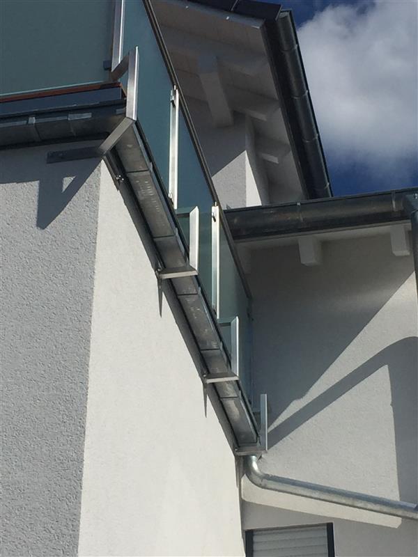 Edelstahl-Dachrinne und Fallrohr an modernem Gebäude mit weißer Fassade, Klumpp Edelstahlverarbeitung Altlußheim.
