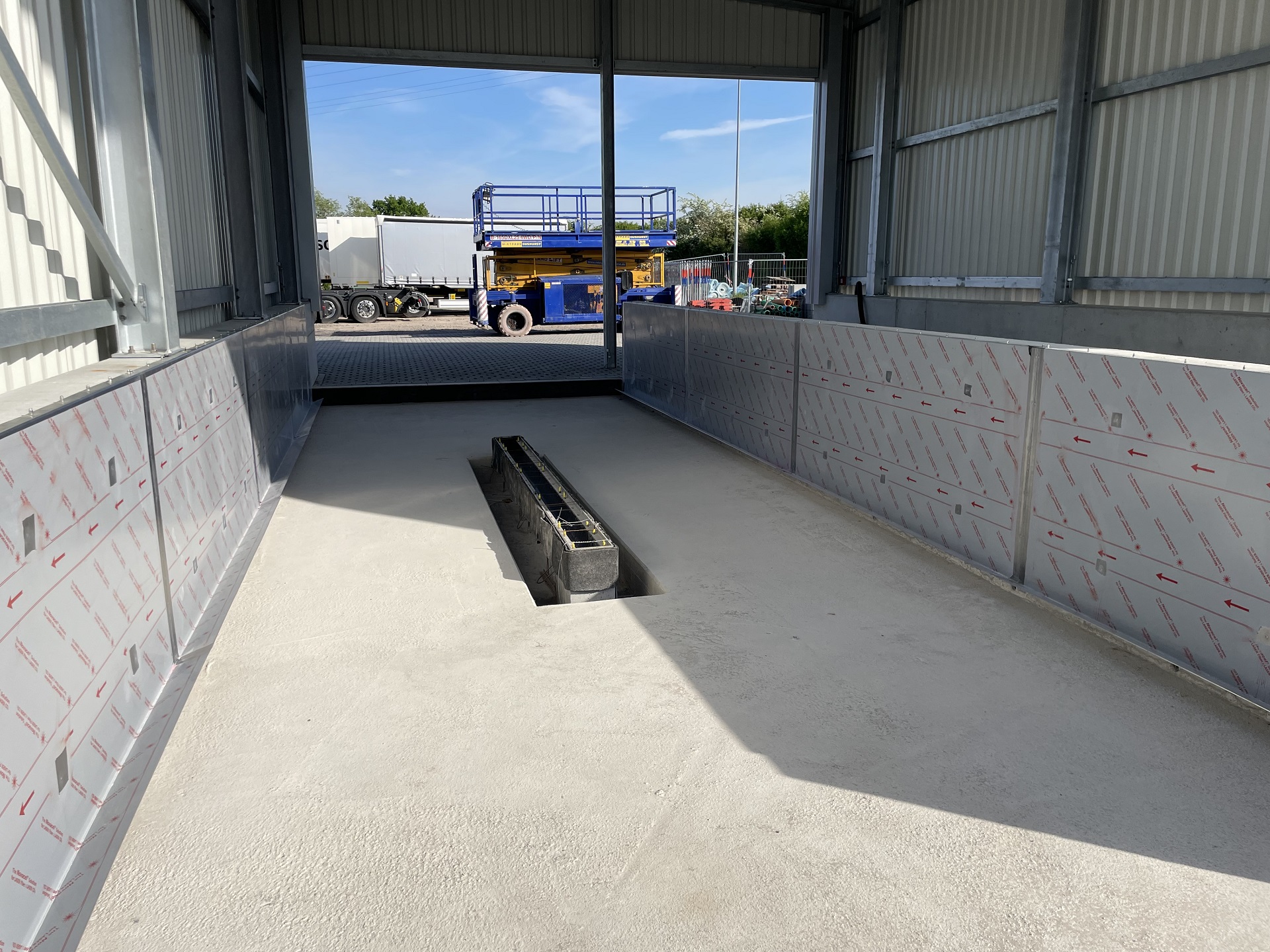 Baustelle mit Betonboden, Wärmedämmung an Wänden und Baumaschinen im Hintergrund bei Klumpp Edelstahlverarbeitung.