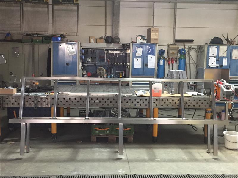 Werkstatt mit langen Arbeitstischen, Werkzeugwänden, Schränken und Maschinen. Industrielle Ausstattung für Edelstahlverarbeitung und Wasserstrahlschneiden.