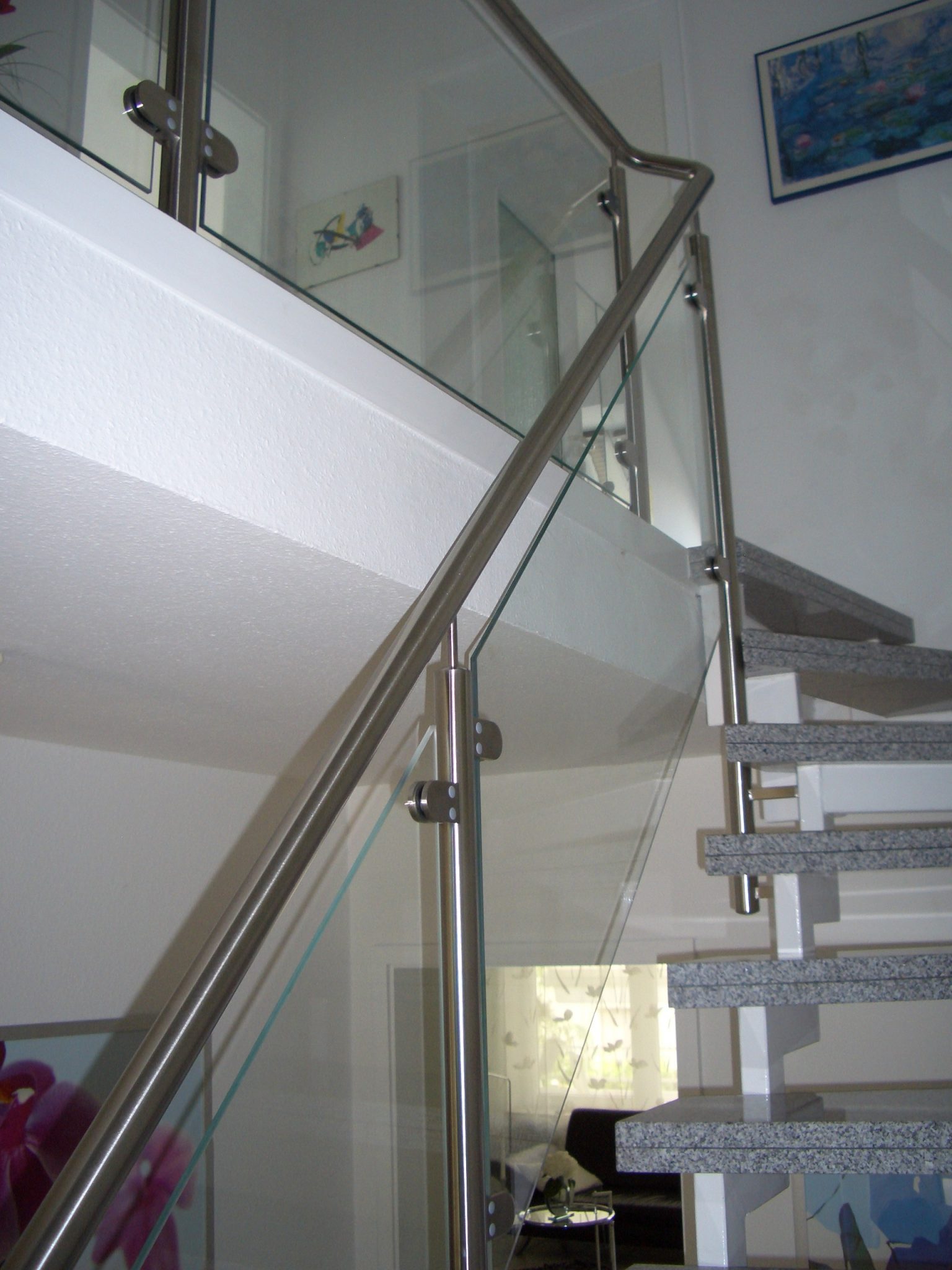 Moderne Edelstahl-Glastreppe mit Handlauf und Drahtseilen, helle Innenarchitektur in zeitgenössischem Design.