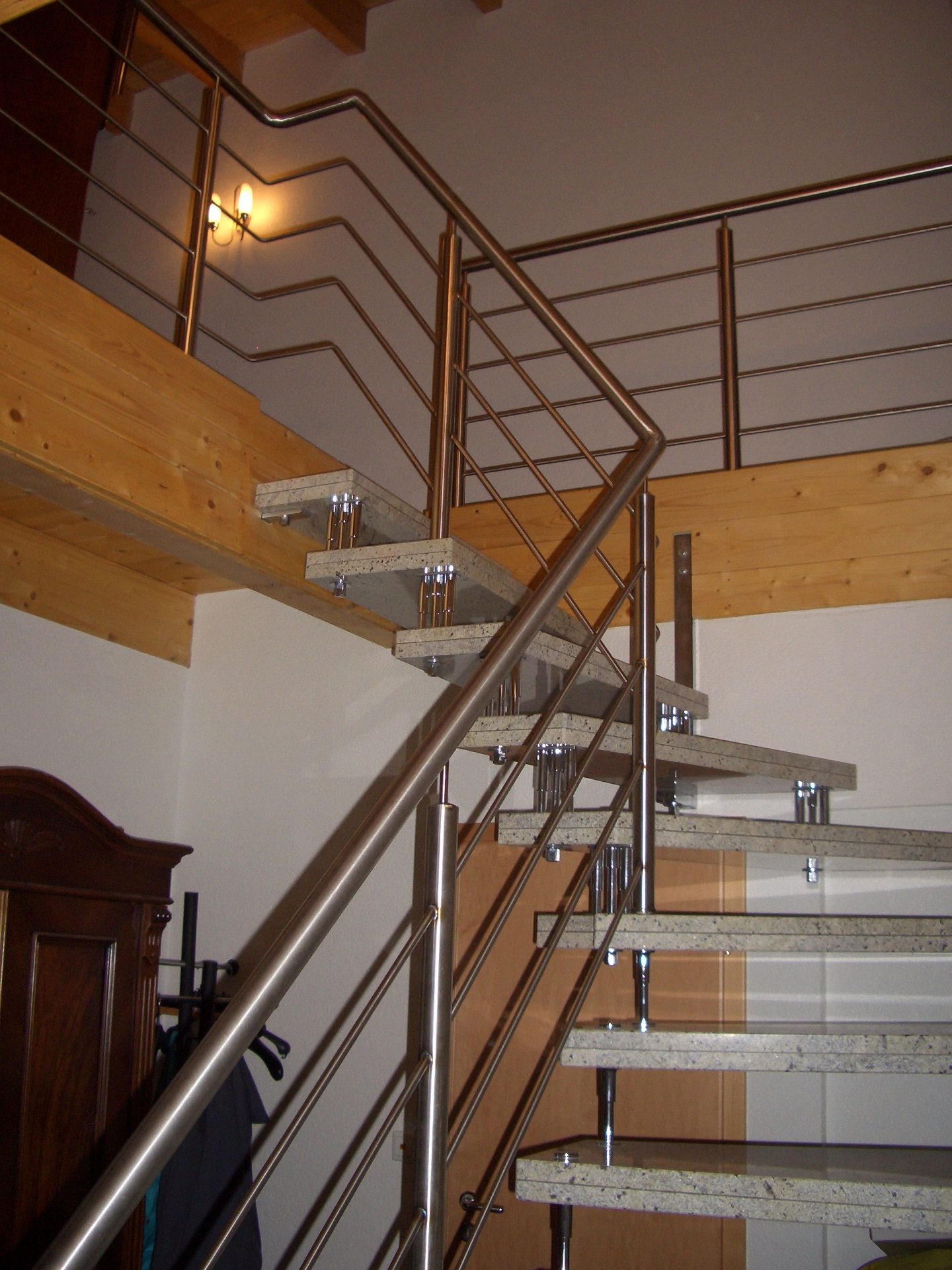 Moderne Stahltreppe mit Edelstahl-Geländer und Holzstufen in Wohngebäude, charakteristisches Handwerk von Klumpp Edelstahlverarbeitung.