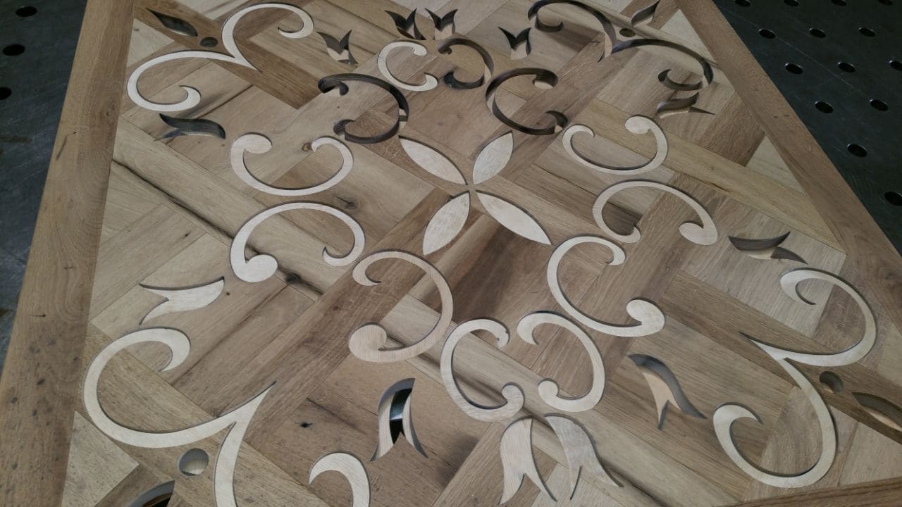 Holzintarsien mit verschlungenen Ornamenten und floralen Mustern, Wasserstrahlschnitt-Detailarbeit auf Sperrholz-Untergrund.