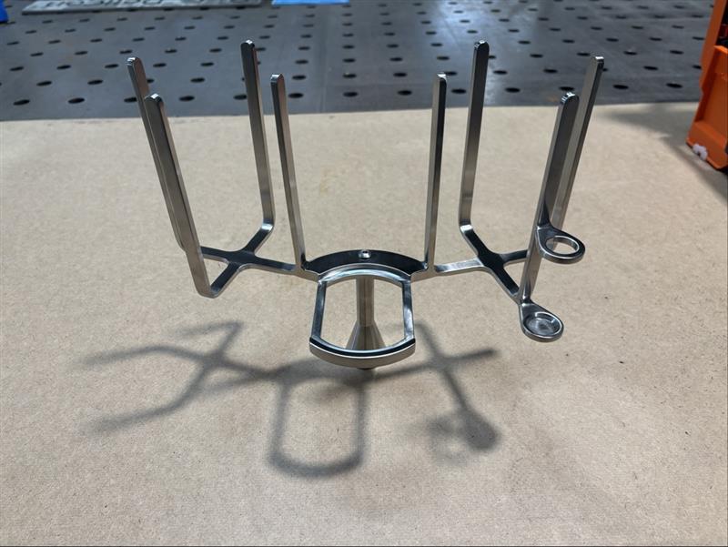 Edelstahl-Halterung mit gebogenen Rohren und Befestigungselementen, professionelle Metallverarbeitung auf Werkstattboden.