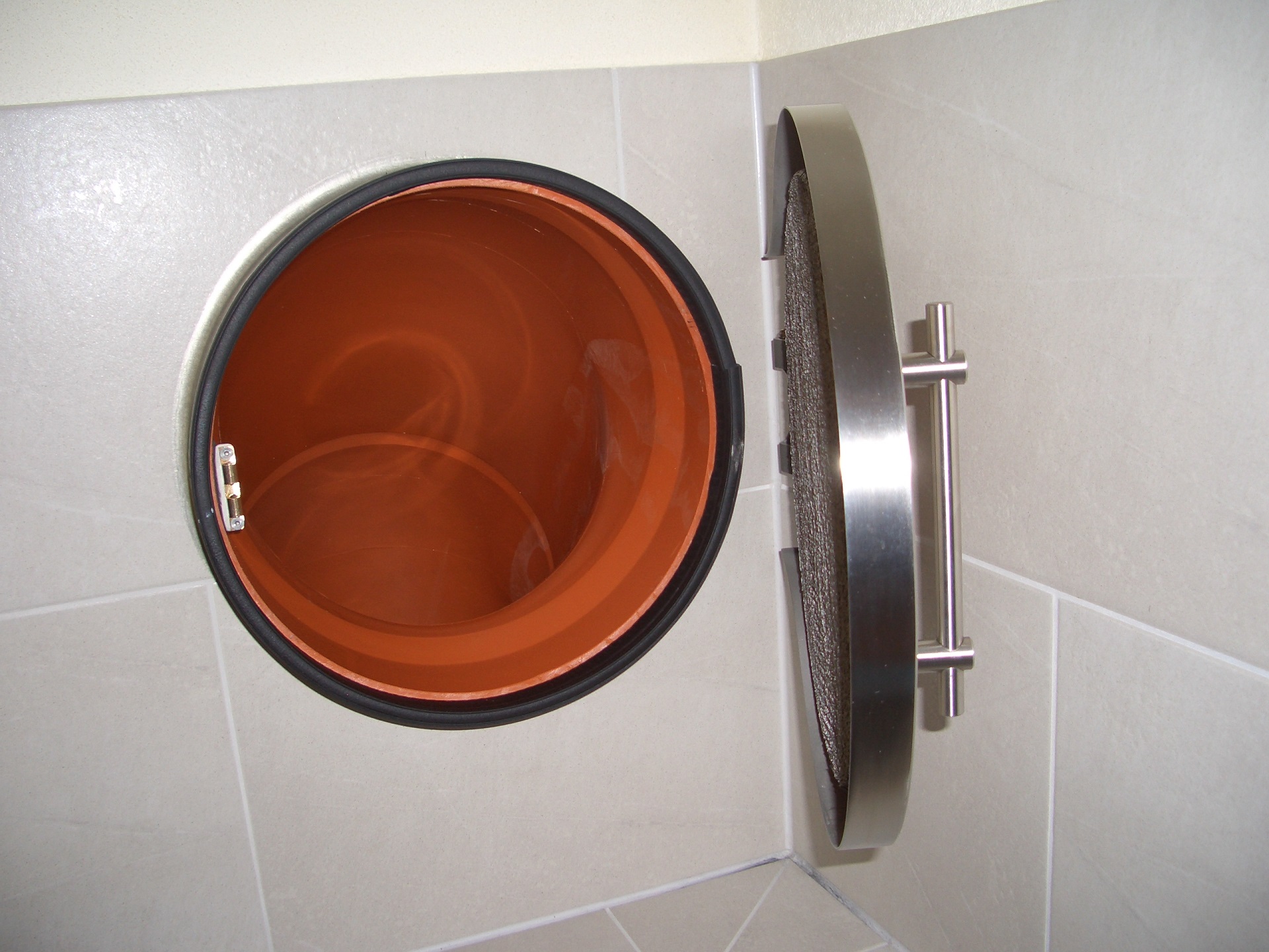 Edelstahl-Rohrbogen mit roter Innenbeschichtung, an weißer Fliesenwand montiert, Qualitätsprodukt der Metallverarbeitung.