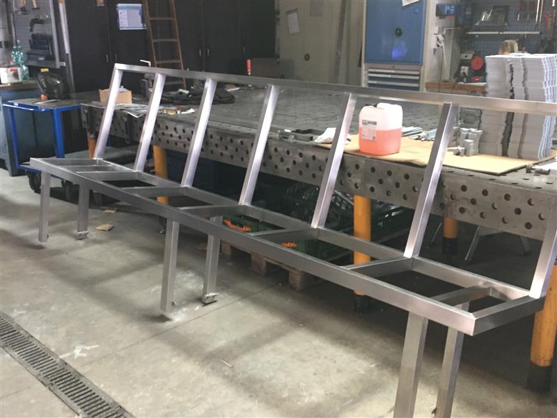 Edelstahl-Werkbank mit Spritzschutz und Werkzeugen in modernem Produktionsbetrieb für Edelstahlverarbeitung.